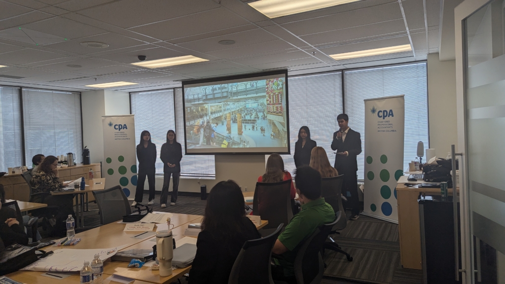 A team presenting their business idea during the JA Company Program summer camp pitch competition, showcasing a marketplace image on the screen.